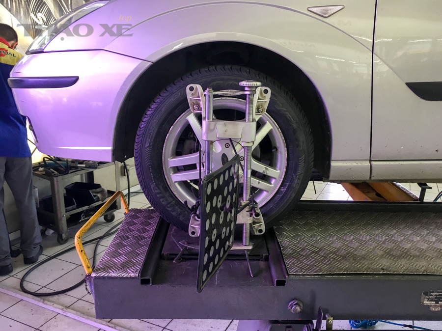 Hình ảnh xe trong bối cảnh bảo dưỡng, minh họa chủ đề kiểm tra và căn chỉnh bánh xe