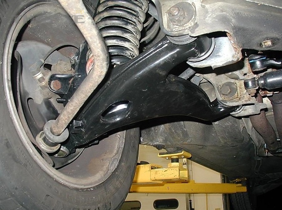 Kỹ thuật viên kiểm tra gầm xe để chẩn đoán tiếng kêu hệ thống treo ô tô