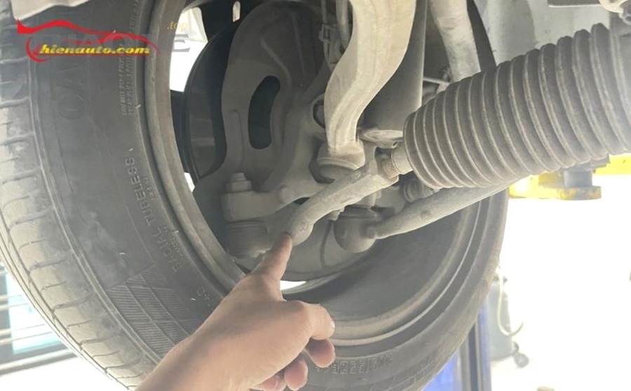 Kỹ thuật viên kiểm tra hệ thống treo và rotuyn ô tô bằng đèn pin