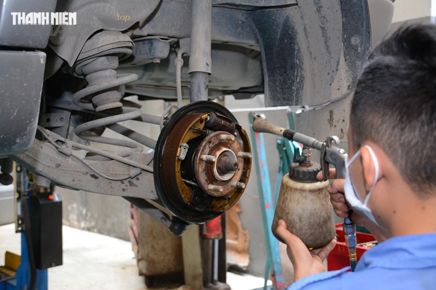 Kỹ thuật viên kiểm tra đĩa phanh, heo phanh và má phanh ô tô